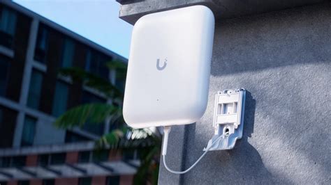 Imagen de un Access Point Ubiquiti UAP-AC-M instalado en una pared exterior.